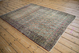 Corner of antique Kerman rug showing intricate boteh, Rococo leaves, worn texture, tattered edge.
