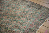 Worn texture with exposed foundation on the antique Kerman rug, showing faded jade green botehs.