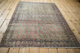 Antique Kerman rug corner, intricate Rococo border, and worn field of repeating botehs.
