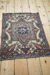 Angled perspective of an antique Kerman rug fragment's central medallion and boteh corner spandrels.