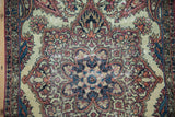 Antique Kerman rug's medallion and boteh motif, showing detailed wear to the knot heads.