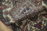Hand-knotted texture and visible foundation on a rolled antique Persian Kerman rug.