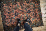 Antique Mehriban rug with dusty rose and sapphire blue Herati motif, showing visible wear underfoot.