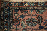 Antique Mehriban rug detail: dusty rose field, sapphire palmettes, serrated leaves, tattered fringe.