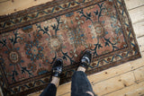 Antique Mehriban rug detail showing sapphire blue curvilinear border, dusty plum field, and visible aged pile.