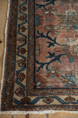 Antique Mehriban rug border close-up: sapphire blue serrated vine with palmettes, dusty plum field with wear.