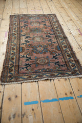 Tattered corner of antique Persian Mehriban rug, dusty plum field, blue vinery, pile wear.