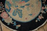 Dark navy border of the antique Art Deco rug, with dusty rose, sky blue, and jade green floral patterns on hand-knotted pile.