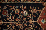 Close view of hand-knotted pomegranate and floral motifs on a dark navy blue pile.