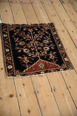 A full, angled view of an antique Farahan Sarouk rug with its central tree of life motif.