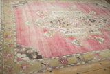 Abrashed raspberry field with ornate Rococo medallion on a distressed vintage Kars carpet.