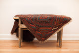 Balouch rug corner with rhythmic red, mallard green geometric pattern and tattered ends.