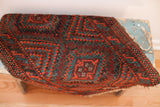 Tribal Balouch rug, rhythmic geometric pattern in mallard green and deep red, with a tattered edge.