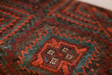 Textured tribal Balouch rug detail with rhythmic patterns, mallard green and rustic red.