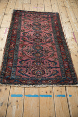 Antique Lilihan rug end detail, showing tattered fringe, dusty magenta field, and teal-outlined birds.