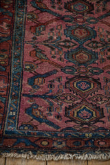 Dusty magenta antique Lilihan rug runner corner with teal motifs and frayed fringe.