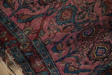 Folded side of the antique Lilihan rug, revealing tattered edge and aged dusty magenta pile.
