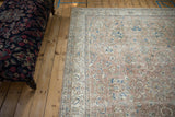 Distressed Oushak rug featuring sapphire blue floral palmettes and vinery on dusty mauve.