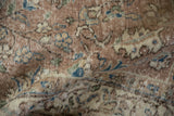 Distressed Oushak rug pile with visible wear, featuring blue and beige floral motifs.