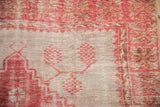 Distressed Oushak rug showing worn pile, raspberry red geometric patterns on ivory.