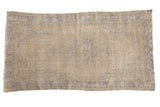 Distressed vintage Oushak rug, faded antique ivory field, pale blue medallion and corner spandrels.