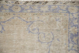 Distressed vintage Oushak rug corner showing worn pale royal blue spandrel on antique ivory.