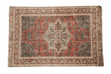 Distressed vintage Sparta rug with a geometric starburst medallion in faded red, teal, and sand.