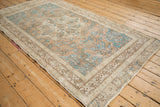 Corner detail of distressed Vintage Sparta rug with faded turquoise blossoms on ochre field and beige geometric borders.