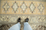 Distressed vintage Turkish Melas rug, gold field with floral diamonds and worn pile.