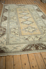 Ochre and oxidized silver floral medallion with dark chocolate brown border on distressed Melas carpet.