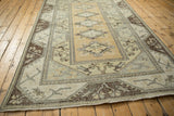 Distressed lower corner of Melas carpet, dark chocolate brown border, and visible foundation.
