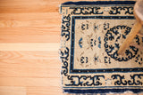 Tattered dark blue pearl border on an Early Peking rug fragment's ivory field.