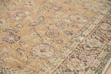 Close-up of a distressed Sparta carpet's worn pile, showing faded pink and sage floral details.
