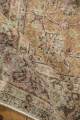 Distressed, low-pile texture of a vintage Sparta carpet with faded pink and sage floral patterns.