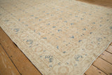 Corner of distressed Sparta rug, worn beige texture, navy blue blossoms, and subtle vinery.