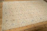 Distressed Sparta carpet corner shows machine-bound edge, faded navy flowers on sandy field.