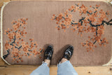 Faintly present embossed cherry blossom petals on a dusty mauve Art Deco rug.