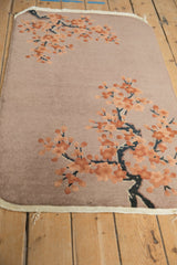 Detailed view of embossed cherry blossoms and branches on a dusty mauve Art Deco rug.