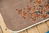 Antique Chinese Art Deco rug corner with terracotta cherry blossoms, dusty mauve field, and tattered ivory selvage.