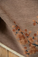 Rolled detail of Antique Art Deco rug, embossed terracotta cherry blossoms on dusty mauve pile.