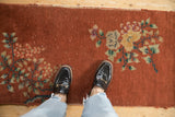 Copper field of antique Art Deco runner with dusty teal floral sprays and visible texture.