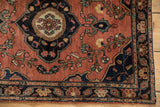 Antique Farahan Sarouk rug corner, dusty brick red field, navy border, and floral vinery detail.