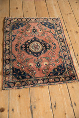 Close-up of antique Farahan Sarouk rug's navy medallion, dusty brick red floral blossoms.