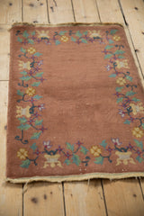 Angled view of antique Chinese Art Deco rug mat, dusty copper with scrolling floral border.
