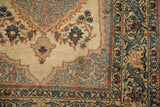 Detail of a vintage Tabriz rug corner showing a minor stain alongside floral and arabesque borders.