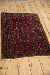 Vintage Sarouk rug mat showing its dense floral pattern on a red field from an angled perspective.