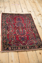 Vintage Sarouk rug mat from an angle, with a cherry red field and thousand flower motif.