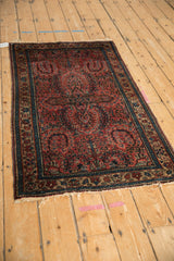 Meandering vine palmette border detail on a vintage Lilihan rug with raspberry floral sprays.