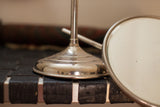 Polished metal base of the antique shaving mirror, showing indentation and beveled oval mirror.