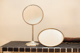 Antique shaving mirrors: silver-toned standing mirror base and oval frame with patina.